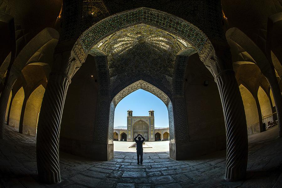 A person stands among buildings in Iran.